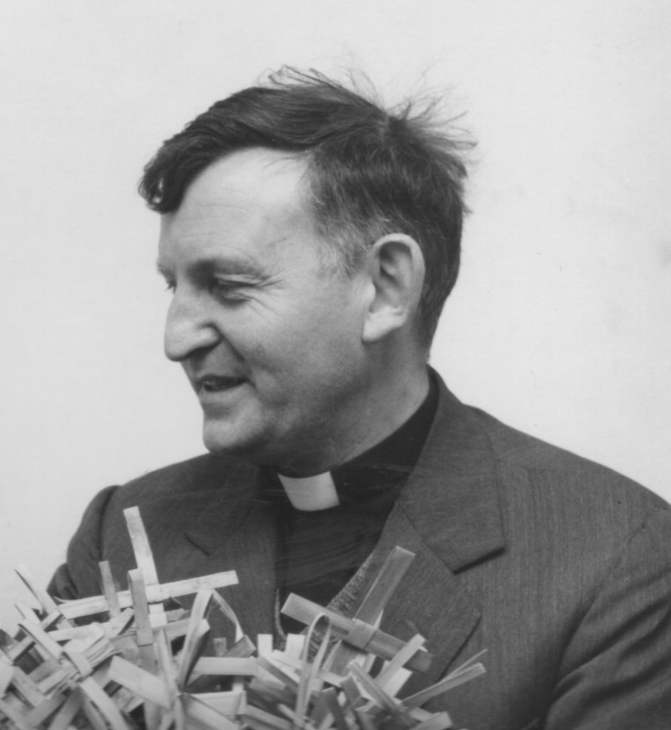 Alan Talbot portrait holding handwoven palm crosses done in Tanzania, Africa